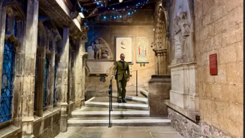 The Reverend Canon Neil Patterson standing half-way down a flight of wide steps in a corner of the cloister