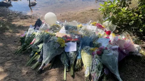 Gemma Dawson/BBC Bouquets of flowers by a lake.