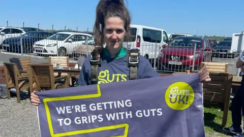 Luned Davies Picture of Luned Davies with a banner for Guts UK after a skydive 