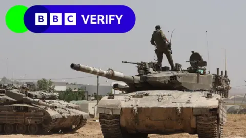 Israeli EPA soldiers ride a tank near the Gaza border. 