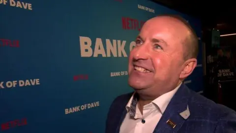 Getty Images Dave Fishwick smile while being interviewed at the premier of the movie Bank of Dave