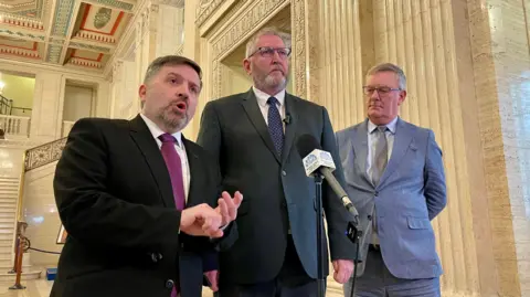 PA Media Robin Swann, Doug Beattie and Mike Nesbitt standing at a podium in Parliament Buildings, Stormont