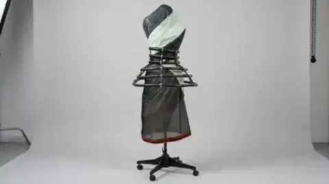 University of Brighton The image shows a dress that has been made out of reused tent material. A hooped skirt can be seen externally, on top of a sheer black base.