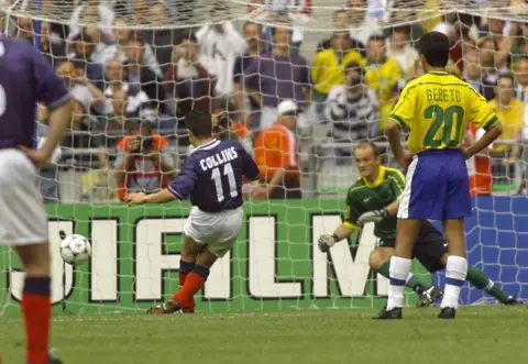 Getty Images Close up view of the goal as John Collins scores on a penalty kick and Brazilian goalie Taffarel dives in vain
