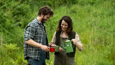 Entertainment Film Distributors Andrew Garfield and Claire Foy in a meadow with cups of tea