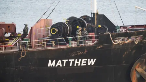 PA Media Black boat with Matthew in white text, military personnel pictured onboard deck