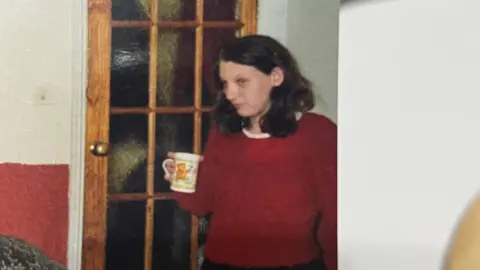 An old photo of Claire Harper holding a mug wearing a red jumper