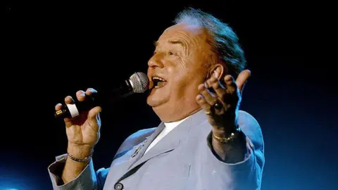 Getty Images Gerry Marsden, wearing a pale grey suit, performs during the Number One Project charity concert at the Echo Arena in Liverpool on 19 January 2008. The event aims to mark Liverpool's status as European Capital of Culture for 2008