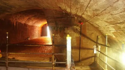 An underground tunnel with a light in the distance