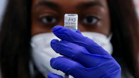 A NHS vaccinator draws the Pfizer COVID-19 second booster jab (fourth dose) to be administered to a woman, at a vaccination centre in London. Older adults have been invited for a fourth Covid-19 dose as part of the spring Covid-19 booster campaign in 2022