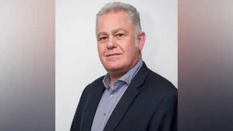 Phil Goodson/UK Hospitality Tony Sophoclides, UK Hospitality's strategic affairs director, looks towards the camera while wearing a shirt and suit jacket, stood in front of a plain white background
