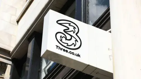 Getty Images A white shop sign with the Three logo on it.