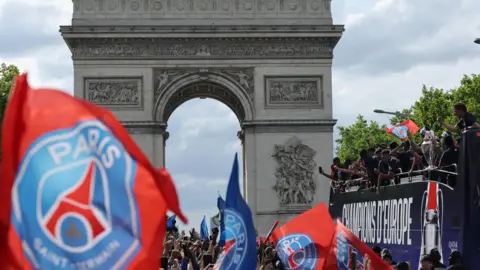 Reuters PSG parading down towards the Arc de Triomphe on an open-top bus, fans holding PSG flags