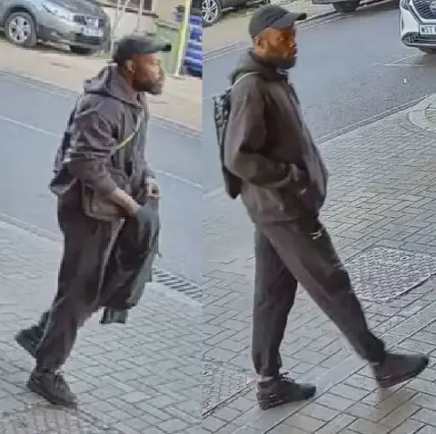 Met Police CCTV-style side-by-side images of a man police want to talk to. He is walking along a paved street, wearing a dark baseball cap, dark hooded jacket, tracksuit bottoms and black trainers, and carrying a backpack; parked cars and a kerb are visible in the background.