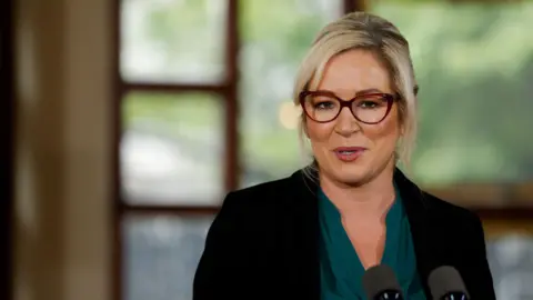 Reuters Michelle O'Neill looking astatine  the camera. She is wearing glasses, a acheronian  greenish  apical  and a achromatic  blazer. The inheritance  of the representation  is blurred. 