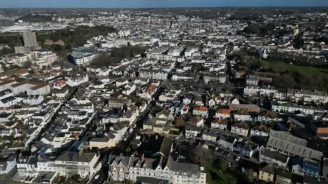 A drone image of Jersey. There are hundreds of houses with some green areas interspersed.