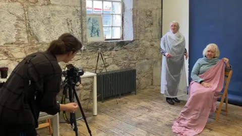 Photographer lines up shot of two women. 