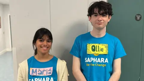 BBC A girl and boy wearing light blue tshirts and name tags