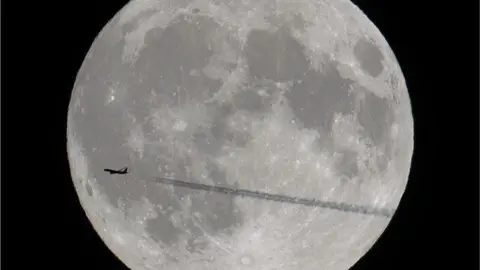 BBC Weather Watcher/Woody's Elf. The silhouette of an airplane crossing the moon.