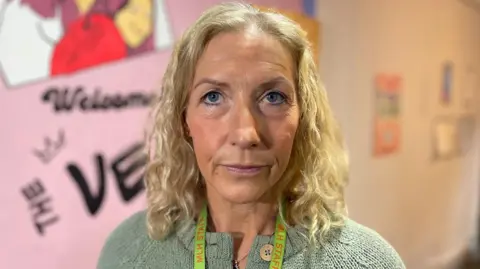 Kate is wearing a green cardigan and has long hair