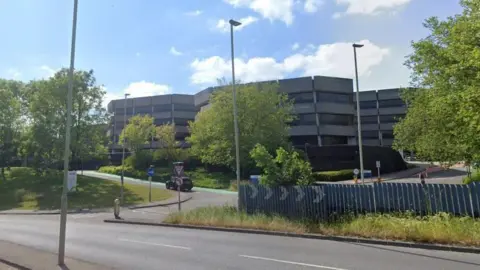 Google A Google street view image of a large office complex. Three octagonal buildings are visible, with alternating rows of concrete walls and windows.