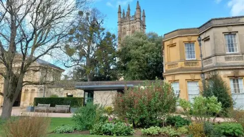 Inside the Oxford Botanic Garden on a sunny day. The Great Tower of Magdalen College can be seen.