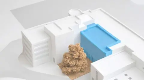 A computer generated image of a college campus with white buildings, which represent the existing blocks. In its centre is a blue block which represents the planned extension. In front of it is an orange area with trees.