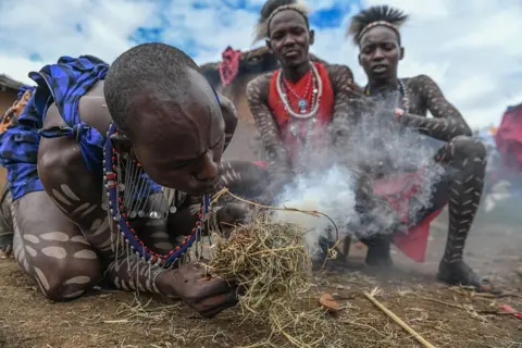 GERALD ANDERSON/GETTY IMAGES A Maasai man blowing smoke in an apparent attempt to make a fire.