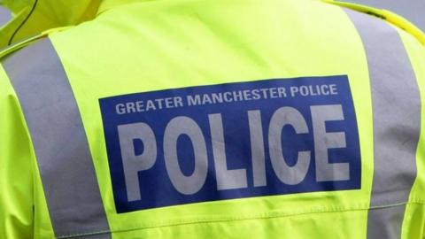 The back of a police officer's hi-vis jacket, saying 'Greater Manchester Police'