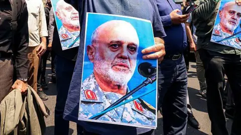 AFP A poster of Gholamali Rashid being held by a protester in Tehran