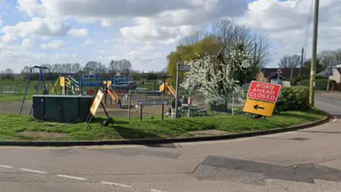 Google Undley Road sign at a junction. There is a Road Ahead Closed sign next to it and a children's playground in the background.