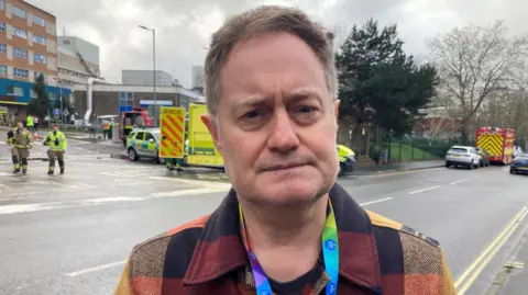 Chief medical officer Paul Grundy in front of the hospital after the fire. The emergency services can be seen behind him.