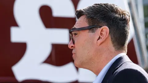 Side profile of Andy Burnham with a large £ sign behind him.