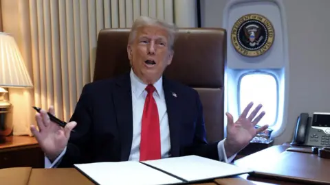 Reuters Trump raises his hands as he talks to reporters aboard Air Force One