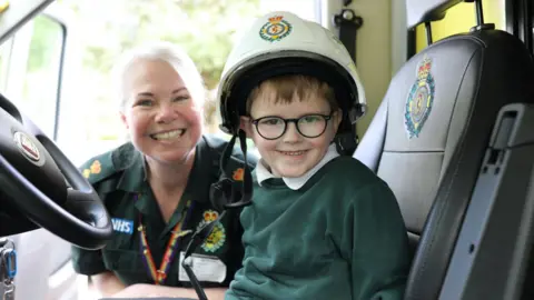 Dimitri Clark in the driver's seat of an ambulance, next to Michelle Behn