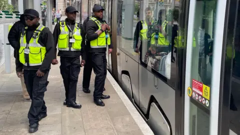 Three of the officers stand outside a tram