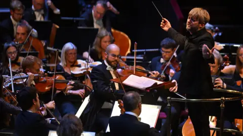 A conductor leads an orchestra during a performance at the Royal Albert Hall.
