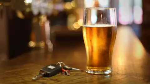 A pint of beer and car keys on a bar