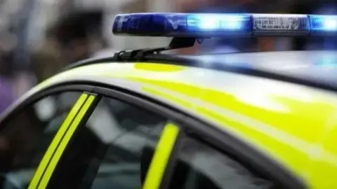 A close-up of the roof of a police car which has its blue lights on.