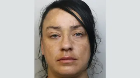 Avon and Somerset Police mugshot of Lisa Bishop. She has dark hair tied back and blue eyes. In the photo she is looking directly into the camera with a blank expression on her face. 