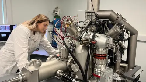 Supplied Madeline Berrow looking into an analytical machine which can test the bacteria-killing effectiveness of their paint.