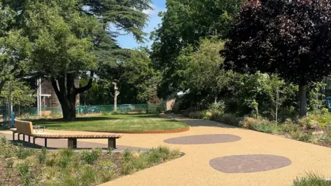 The Peace Garden has wooden benches and a pathway around a green lawn.
