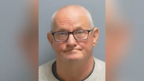 Colin Stear mugshot. He has short white hair and glasses.
