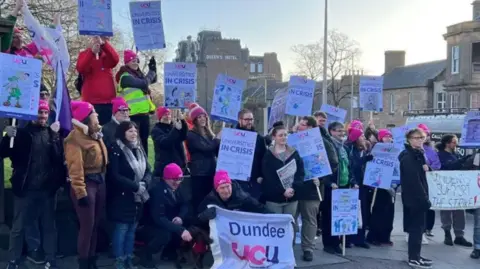 several people holding placards while on a picket line