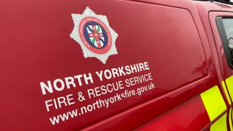 The North Yorkshire Fire & Rescue Service logo on the side of a red fire van