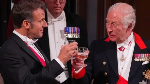 King Charles III and French President Emmanuel Macron raise their glasses towards each other in a toast at a state banquet at Windsor Castle
