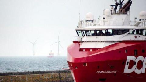 A supply ship in Aberdeen with turbines in the background at sea