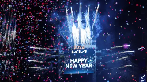Kylie Cooper / Reuters Fogos de artifício explodem e confetes flutuam na frente de uma placa que diz "Feliz Ano Novo" na Times Square de Nova York