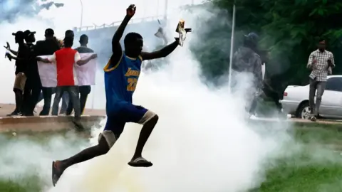 A man is jumping as police are dispersing protesters during the anti government protest in Abuja, Nigeria, on August 2, 2024