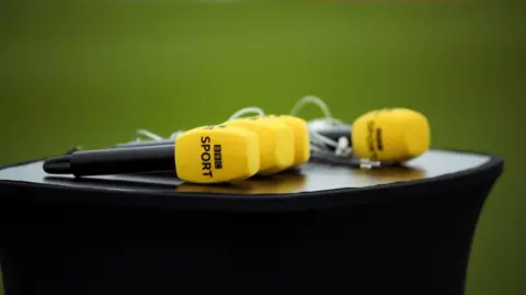 PA Media Four yellow BBC Sport microphones on a table